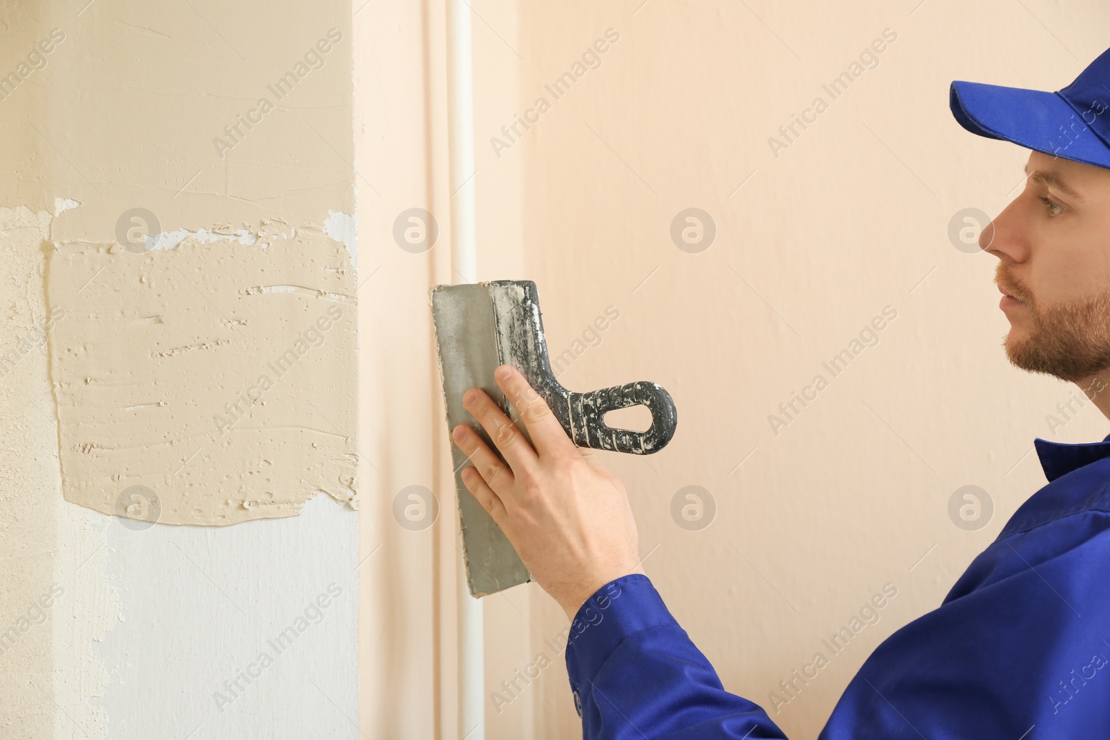 Photo of Professional worker plastering window area with putty knife indoors, closeup. Interior repair