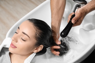 Stylist washing client's hair at sink in beauty salon