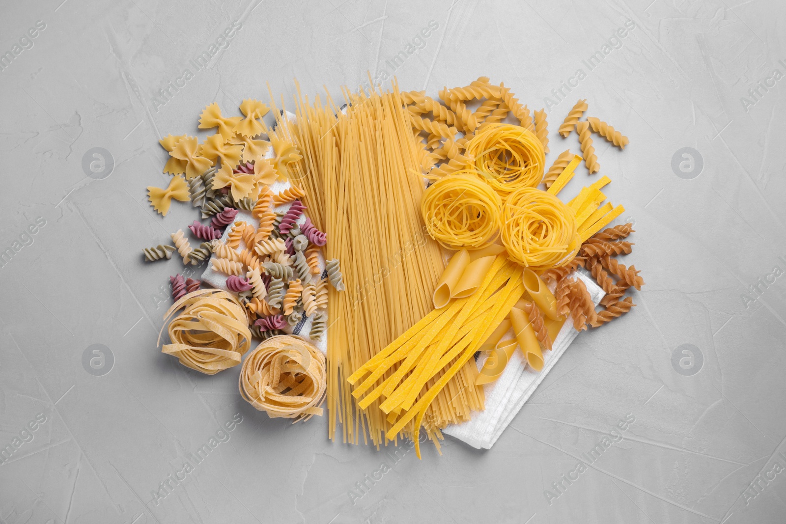 Photo of Different types of pasta on light grey table, flat lay