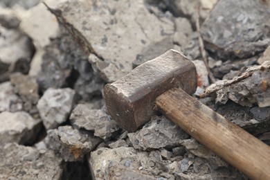 Photo of Sledgehammer on pile of broken stones outdoors, closeup