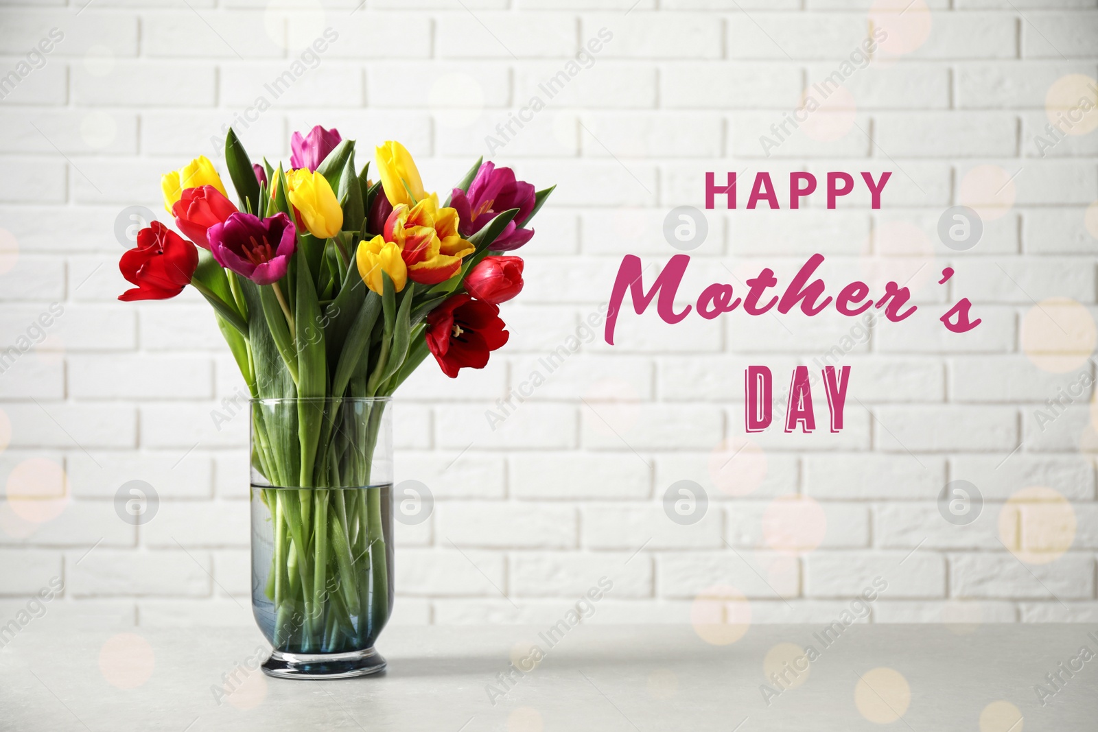 Image of Vase with beautiful tulips and phrase HAPPY MOTHER'S DAY on light table