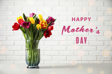 Image of Vase with beautiful tulips and phrase HAPPY MOTHER'S DAY on light table