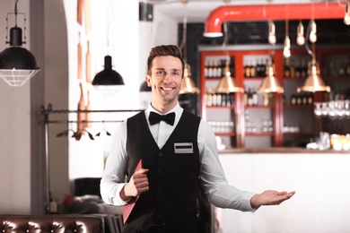 Photo of Waiter in elegant uniform with menu at workplace