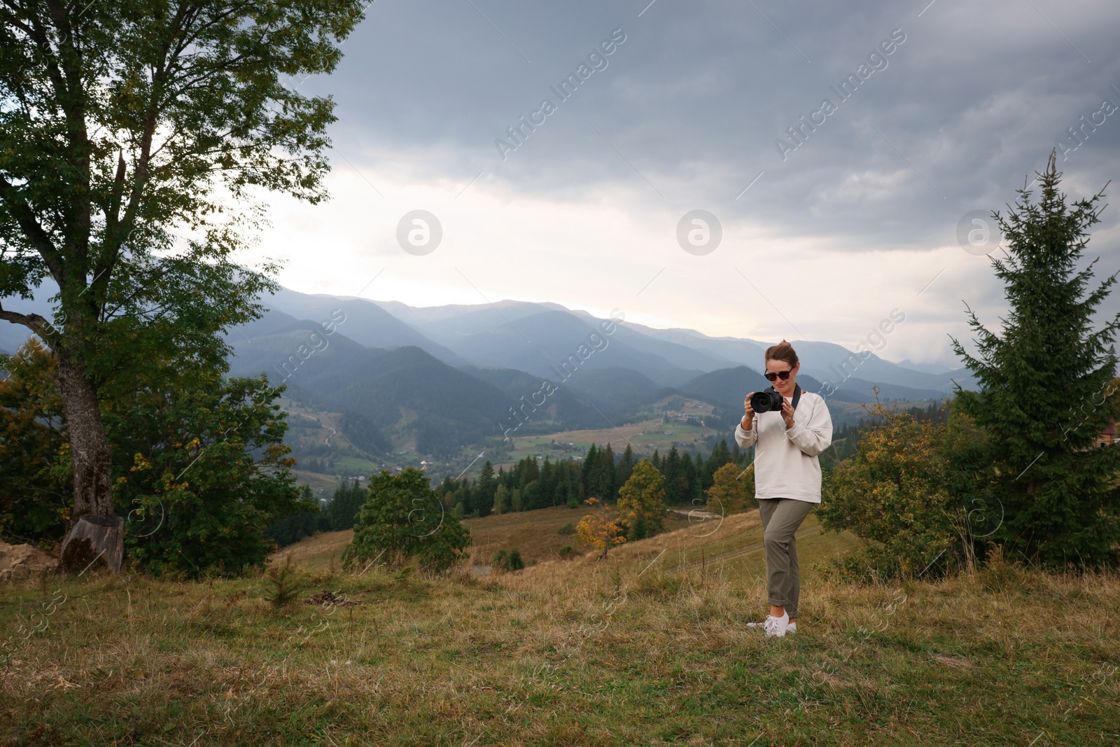 Photo of Professional photographer taking picture with modern camera in mountains. Space for text