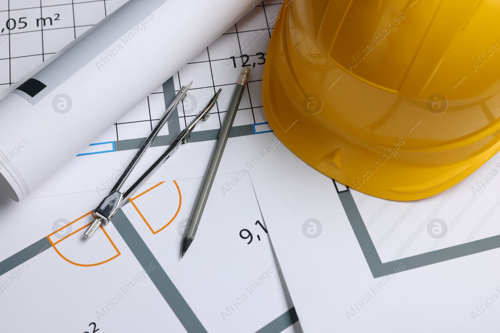 Photo of Rolled construction drawing, safety hat, pair of compasses and pencil on house plan