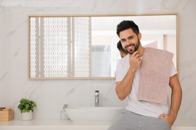 Photo of Handsome young man after shaving in bathroom, space for text