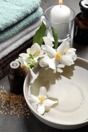 Photo of Beautiful spa composition with jasmine essential oil and fresh flowers on grey table