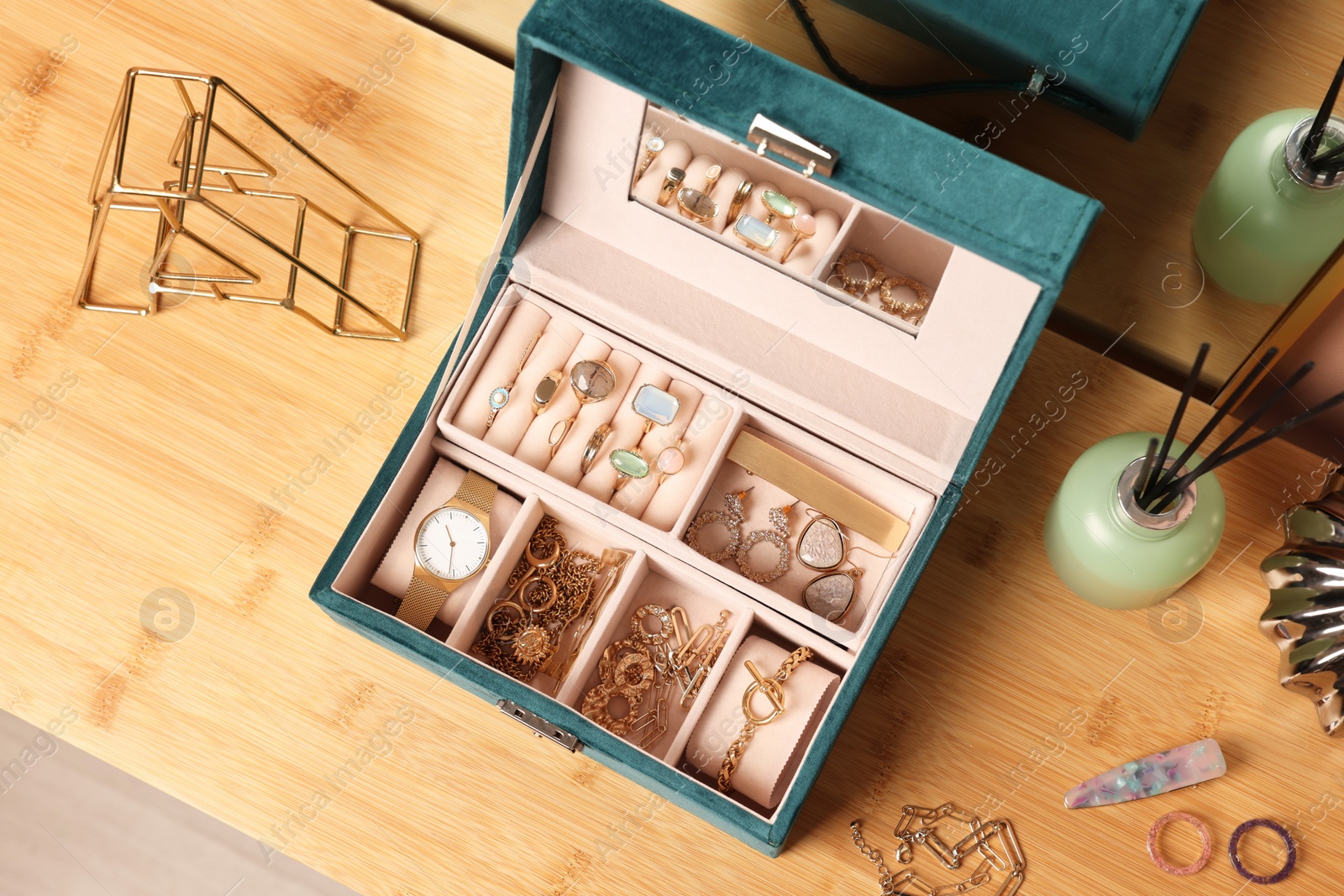 Photo of Elegant jewelry box with beautiful bijouterie and expensive wristwatch on wooden table, top view