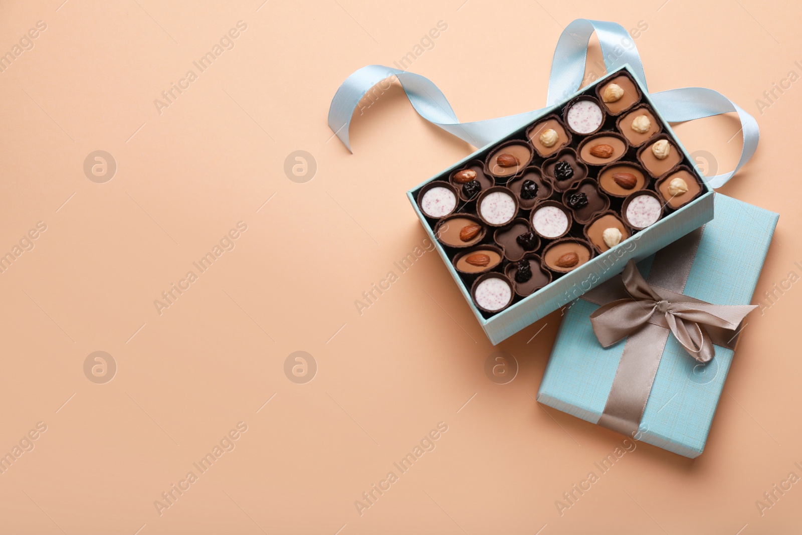 Photo of Box of delicious chocolate candies on beige background, flat lay. Space for text