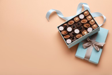 Photo of Box of delicious chocolate candies on beige background, flat lay. Space for text