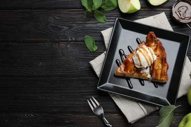 Photo of Slice of traditional apple pie with ice cream served on black wooden table, flat lay. Space for text
