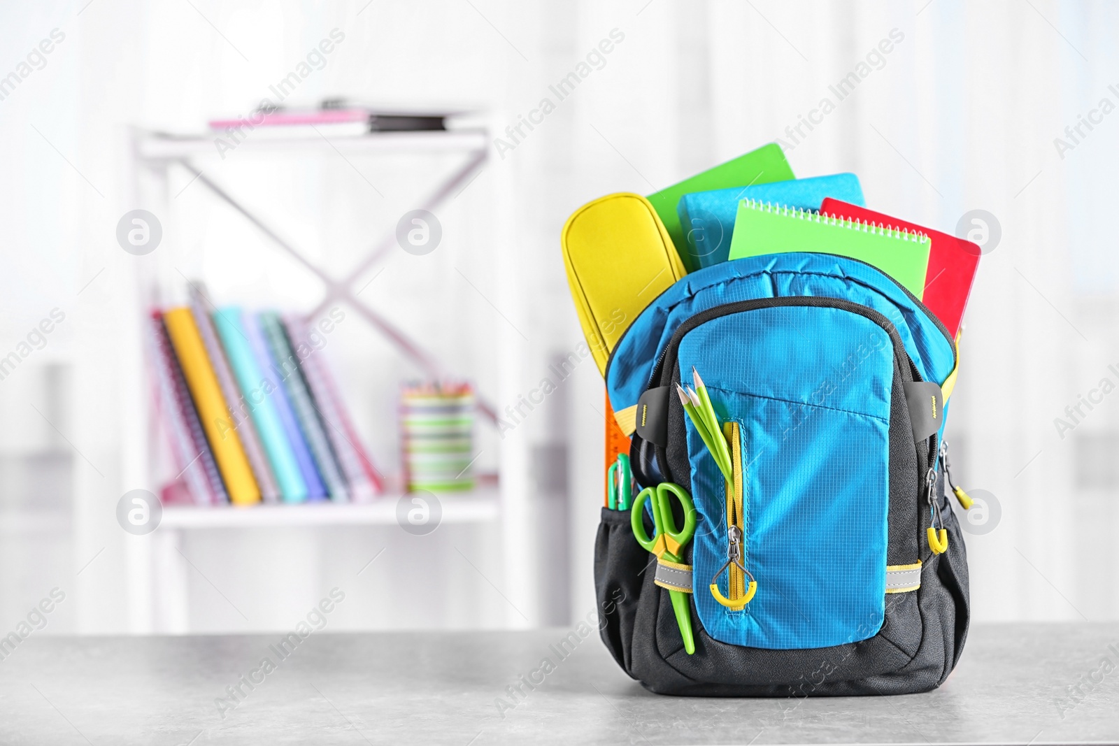 Photo of Backpack with school stationery on table indoors