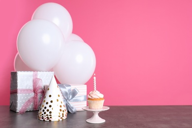 Photo of Composition with birthday cupcake, presents and balloons on table. Space for text