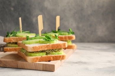 Tasty sandwiches with cucumber and microgreens on textured table. Space for text