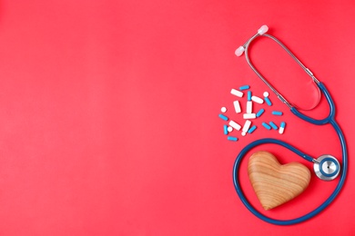 Photo of Flat lay composition with stethoscope, pills and heart on color background, space for text. Cardiology concept