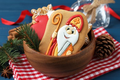 Photo of Tasty gingerbread cookies and fir branches on blue table, closeup. St. Nicholas Day celebration