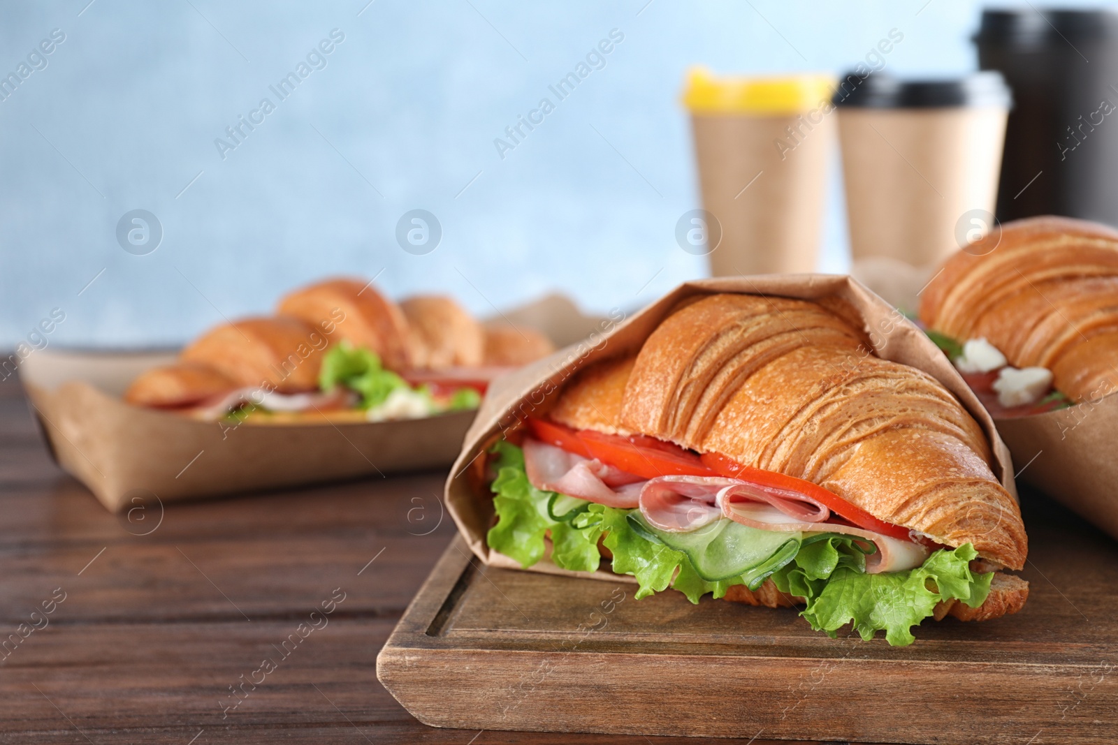 Photo of Tasty croissant sandwich with ham on wooden table, closeup