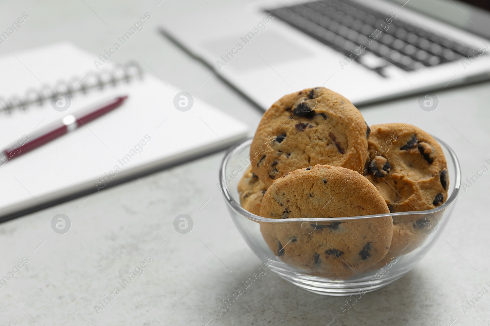 Photo of Chocolate chip cookies on light gray table in office, closeup. Space for text