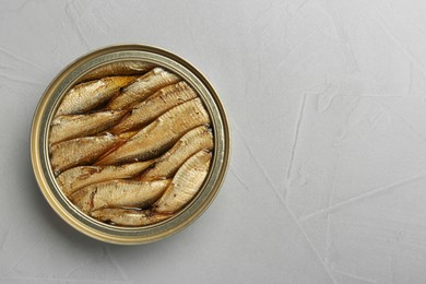 Open tin can of sprats on light grey table, top view. Space for text