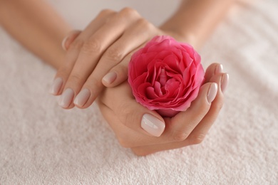 Photo of Woman with smooth hands and flower on towel, closeup. Spa treatment