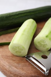 Fresh cucumbers and peeler on table, closeup