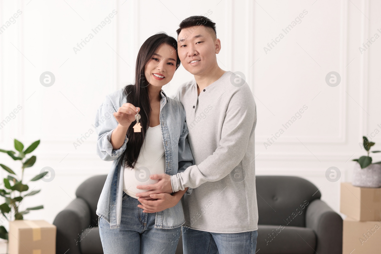 Photo of Pregnant woman and her husband with key in their new apartment