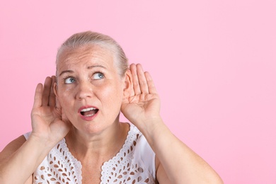Mature woman with hearing problem on color background
