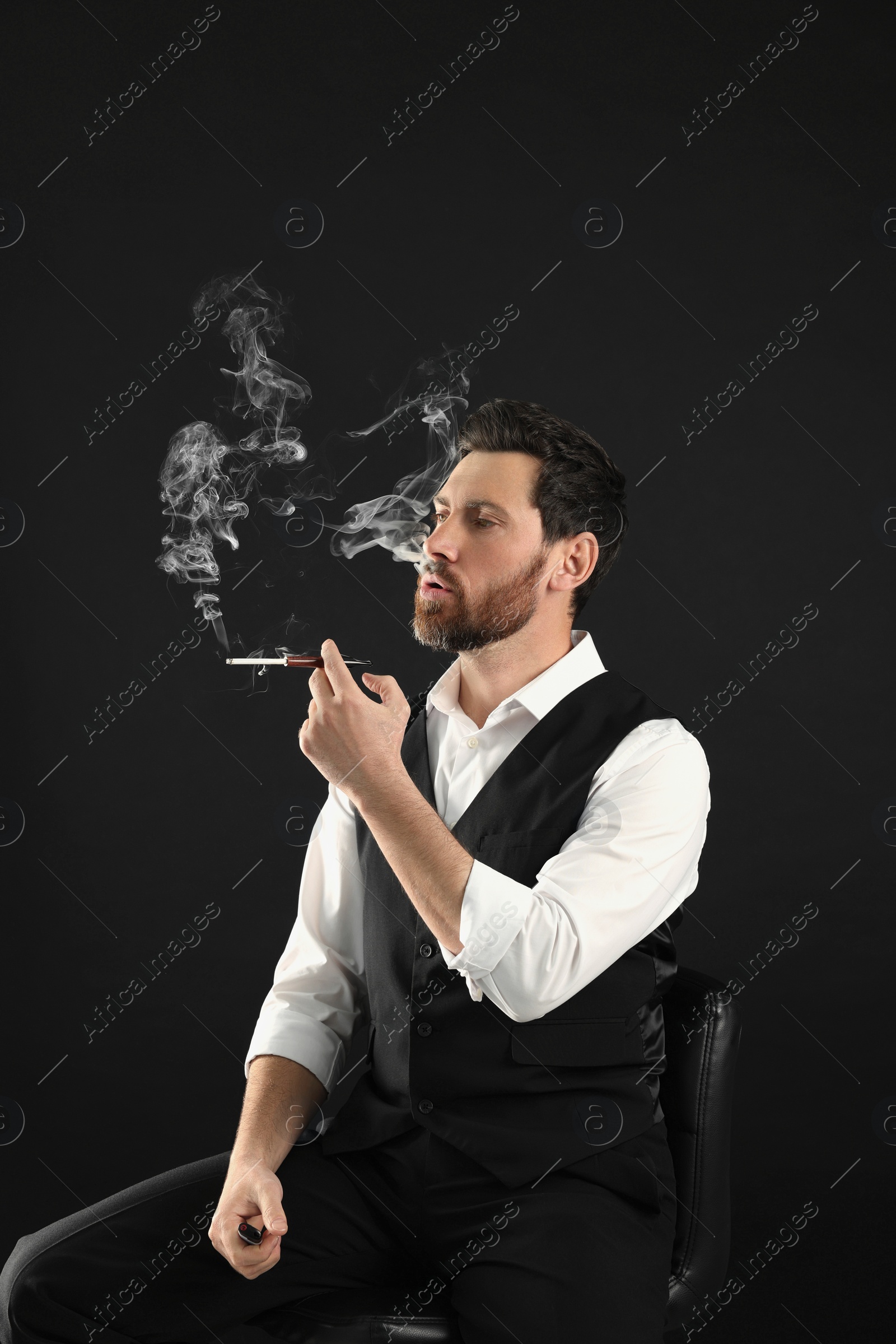 Photo of Man using cigarette holder for smoking on black background