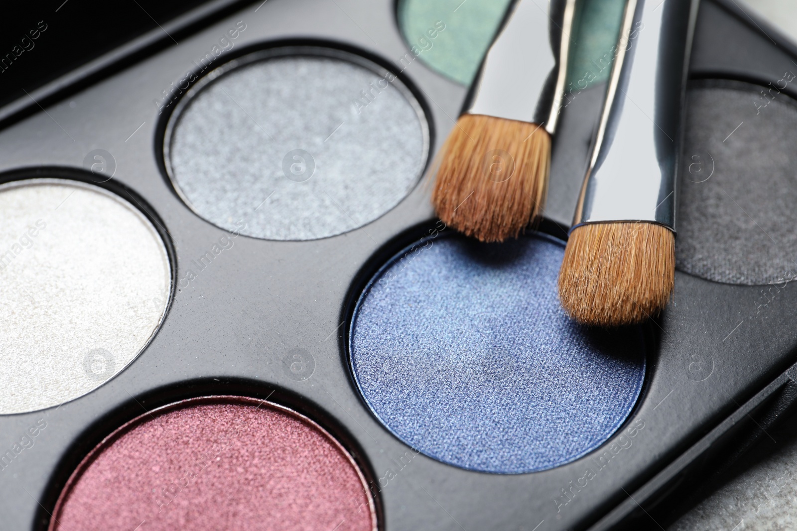 Photo of Beautiful eye shadow palette and brushes on grey table, closeup