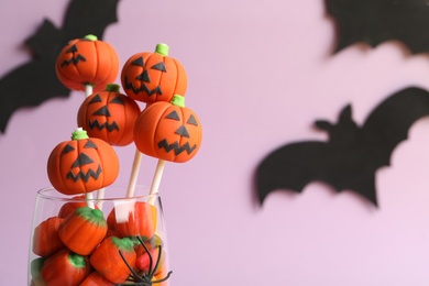 Photo of Delicious Halloween themed cake pops on pink background, closeup. Space for text