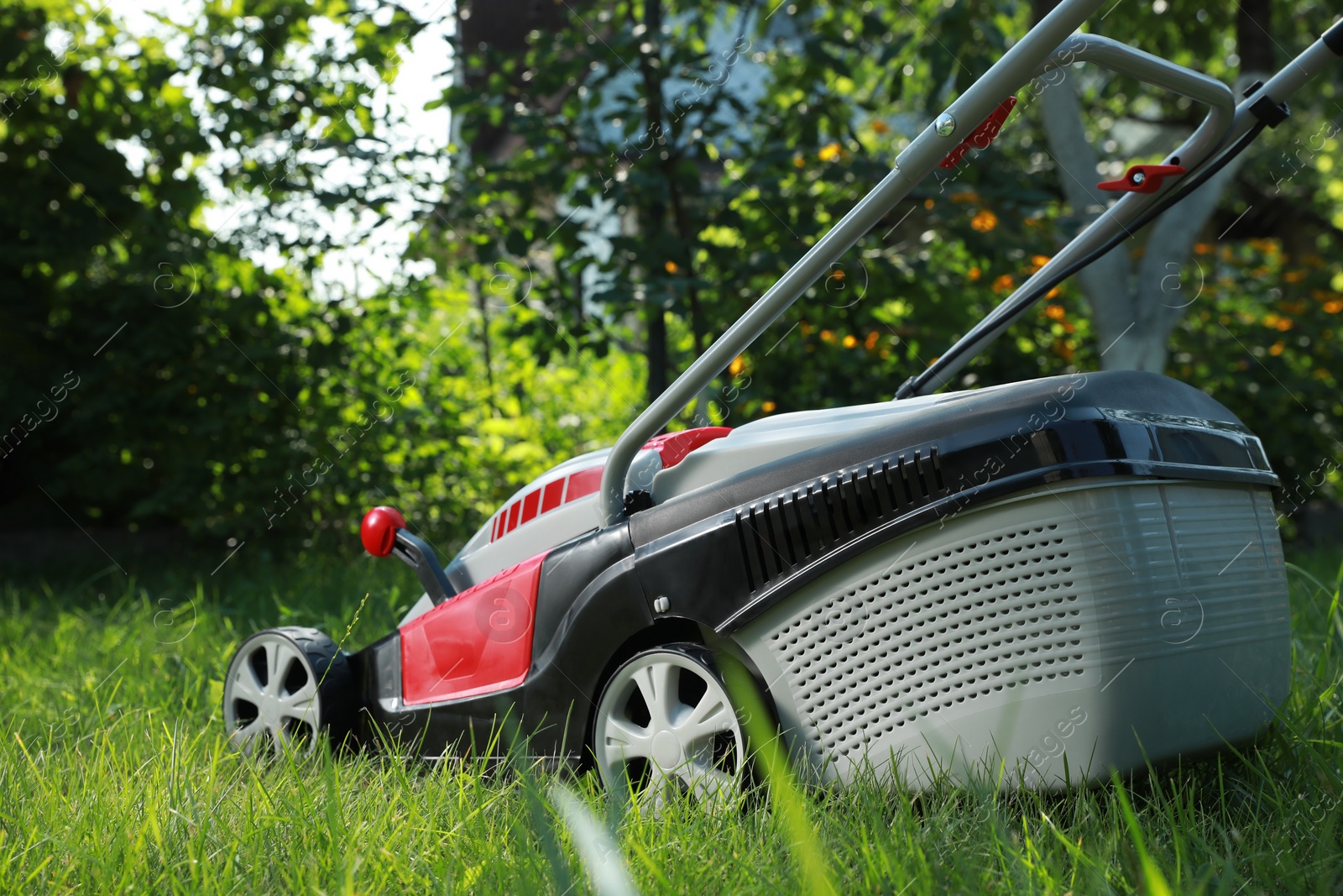 Photo of Lawn mower on green grass in garden