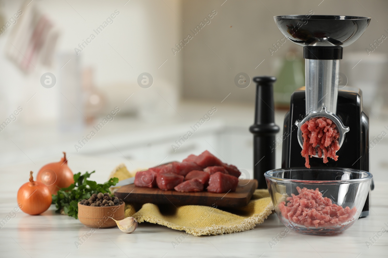 Photo of Electric meat grinder with beef mince and products on white table in kitchen