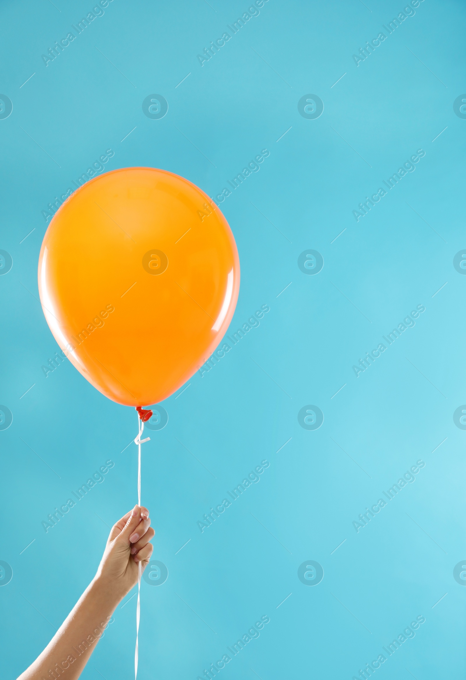 Photo of Woman holding orange balloon for Halloween party on blue background