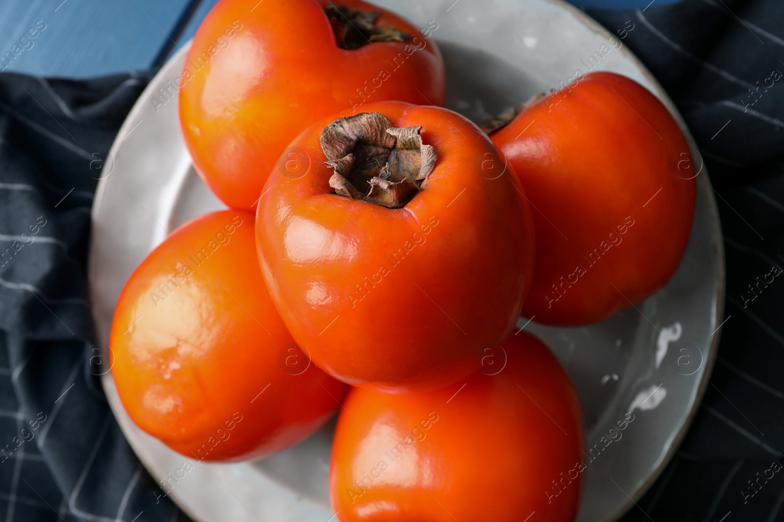 Photo of Delicious ripe persimmons and plate on table, top view