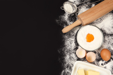 Photo of Flat lay composition with eggs and other ingredients on black table, space for text. Baking pie