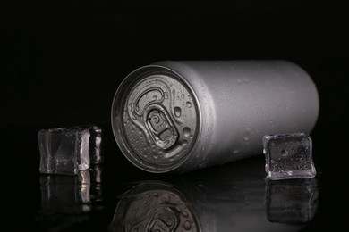 Photo of Energy drink in wet can and ice cubes on black background, closeup