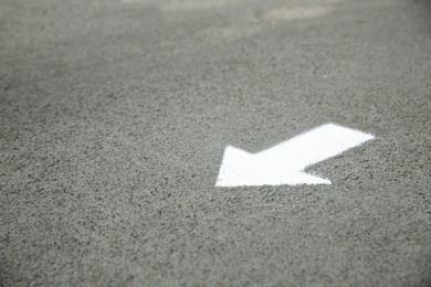 Photo of White arrow painted on asphalt. Space for text