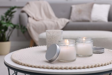 Burning candles in jars on white table indoors, space for text