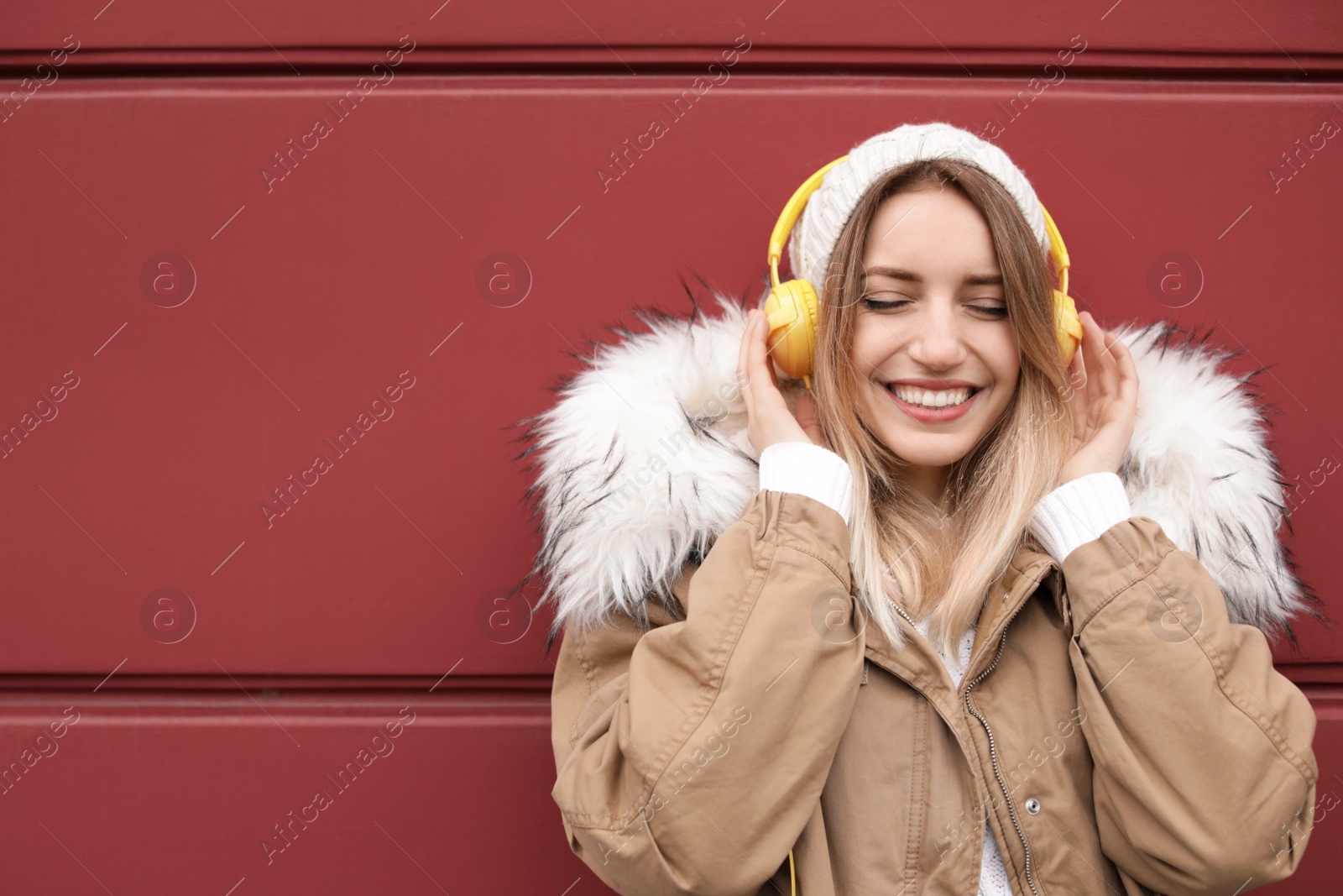 Photo of Young woman with headphones listening to music near color wall. Space for text