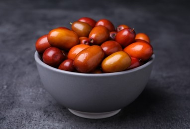 Photo of Ripe red dates in bowl on grey table, closeup