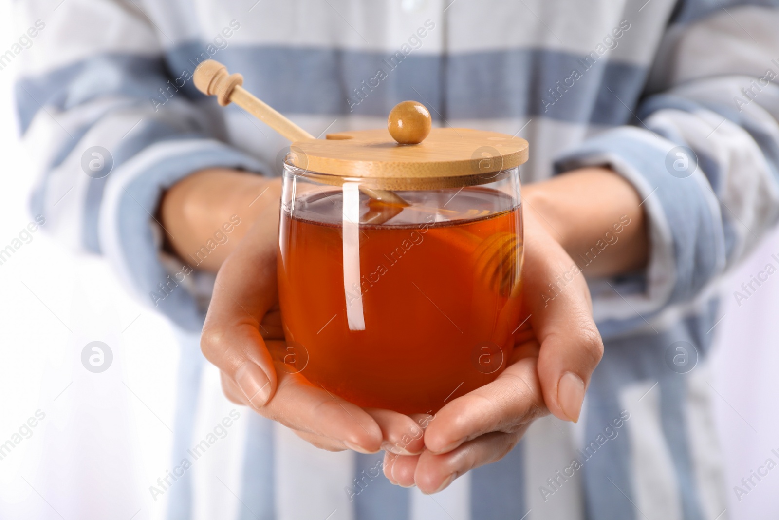 Photo of Woman holding glass jar with fresh sweet honey, closeup