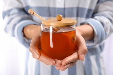 Photo of Woman holding glass jar with fresh sweet honey, closeup