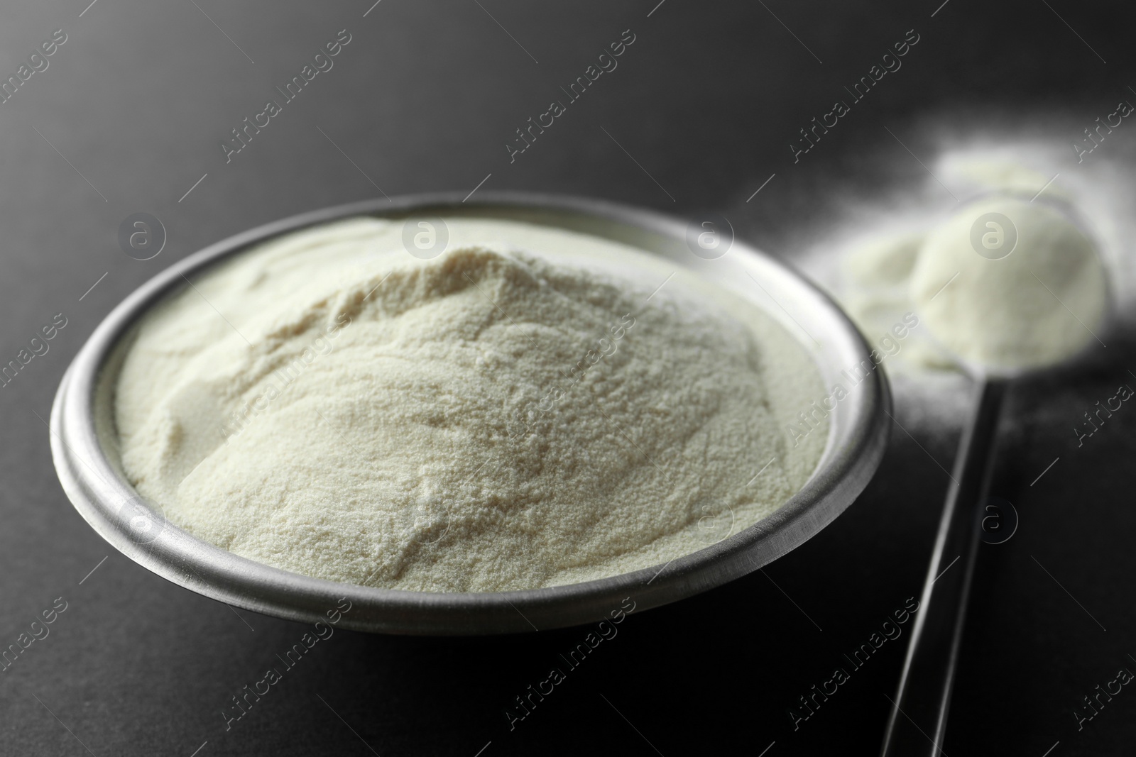 Photo of Bowl and spoon of agar-agar powder on black background, closeup