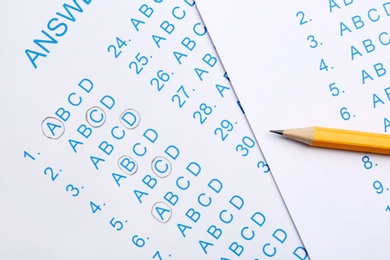 Photo of Orange pencil on answer sheets, top view