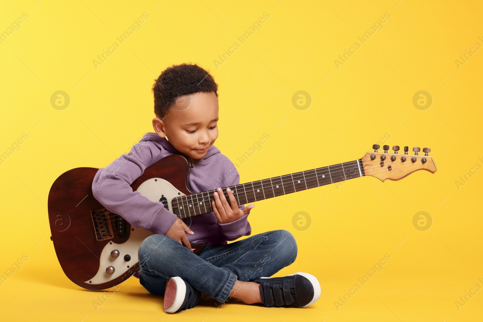 Photo of African-American boy with electric guitar on yellow background