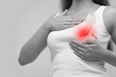 Woman doing breast self-examination on grey background, closeup. Color accent effect