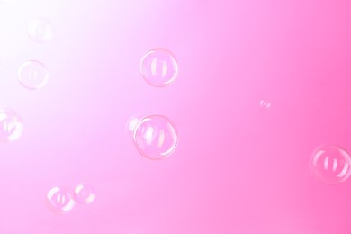 Photo of Beautiful transparent soap bubbles on pink background