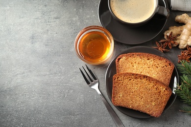 Photo of Fresh gingerbread cake slices served with honey and coffee on grey table, flat lay. Space for text