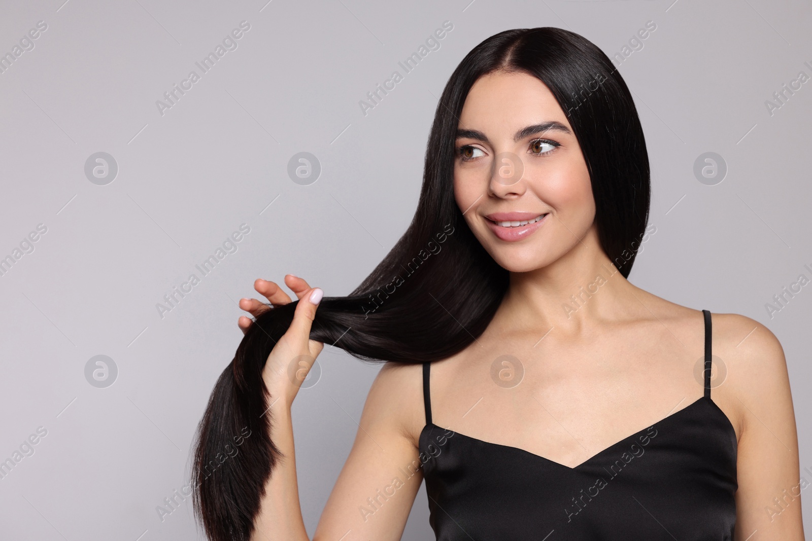 Photo of Portrait of beautiful young woman with healthy strong hair on light grey background. Space for text