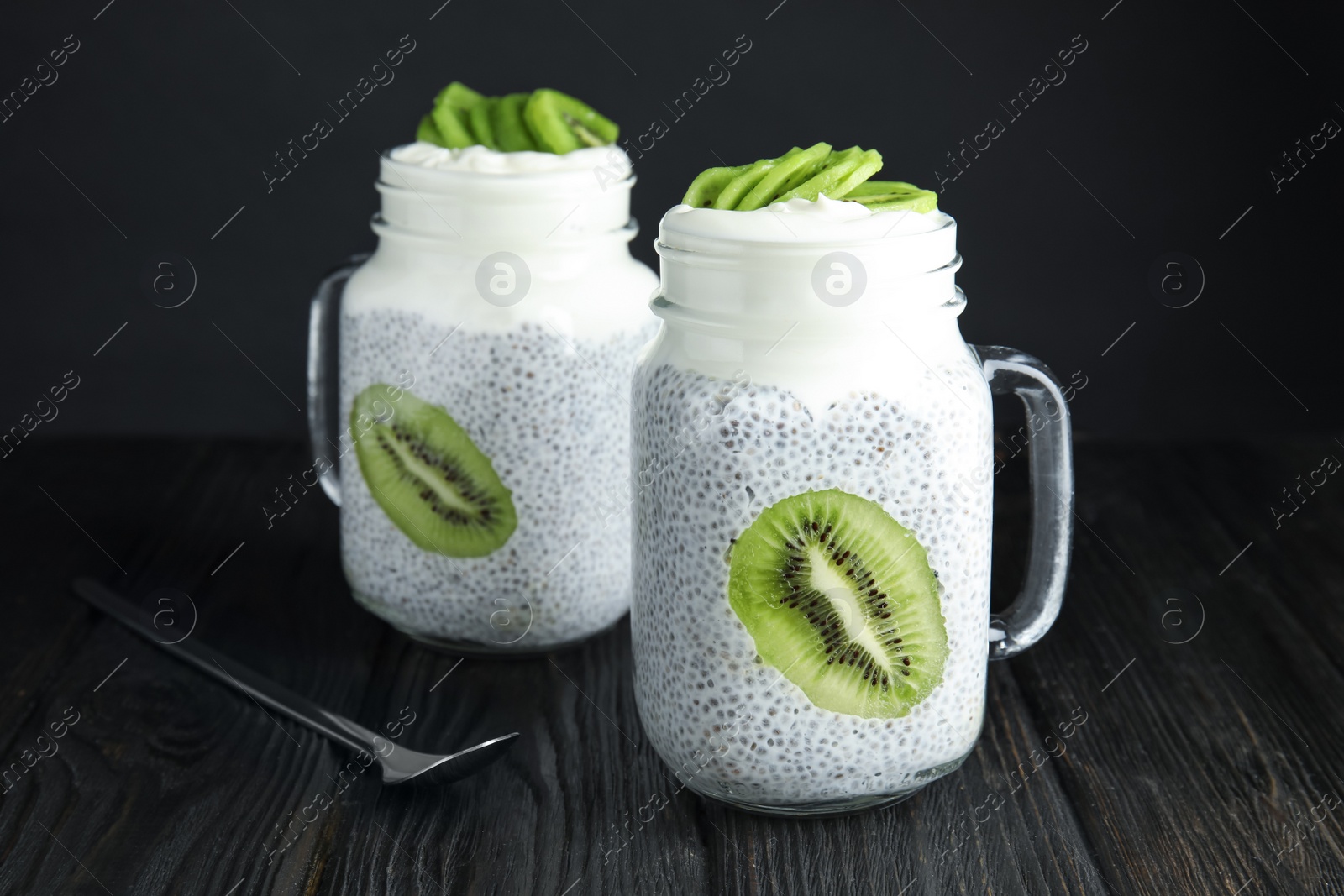 Photo of Mason jars of tasty chia seed pudding with kiwi on table